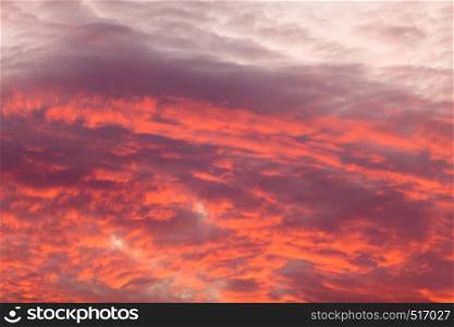 Romantic and dramatic cloud formation on dusk sky. Red and black warm landscape with sunlight.. Colorful warm clouds on sky at sunset