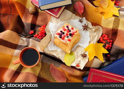 Romantic autumn still life with books, plaid, cake, coffee cup and leaves, top view. Romantic autumn still life