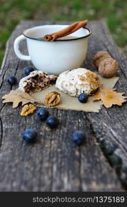 Romantic autumn still life with cookies, cup of tea, walnuts, blackthorn berries and oak leaves. Romantic autumn still life