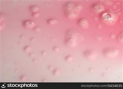 Romantic background from pink fluid and drops on white