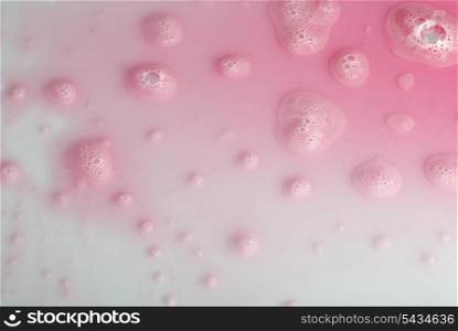 Romantic background from pink fluid and drops on white
