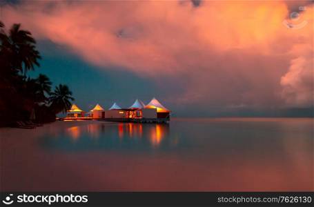 Romantic beach landscape, little restaurant on the bank of tropical island at the evening, summer vacation on a luxury resort, Maldives