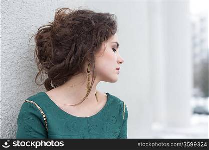 Romantic Caucasian Woman in Green Dress over White Wall outside. Solitude