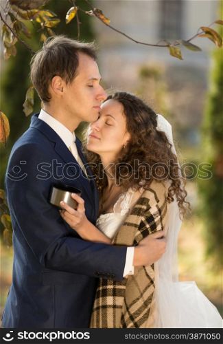 Romantic closeup portrait of bride and groom hugging at park at warm sunny day