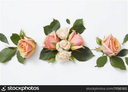 Romantic composition from beautiful roses flowers on a light grey background with copy space. Flat lay. Greeting card for Valentine&rsquo;s Day.. Flowers card with roses and green leaves.