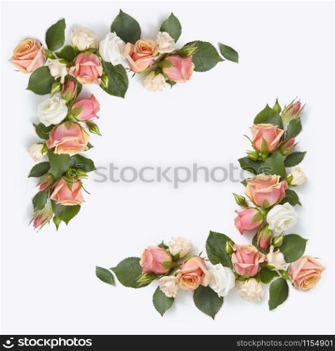 Romantic congratulation corner frame from roses flowers with green leaves on a light grey background, copy space. Flat lay.. Square corner flowers frame from roses and leaves.