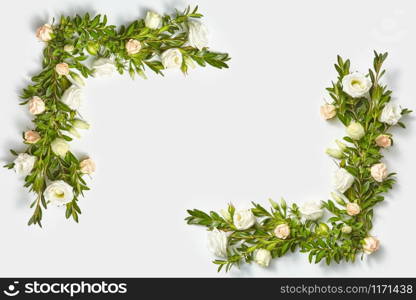 Romantic corner frame from boxwood evergreen branches with flowers on a light grey background with copy space. Flat lay. Valentine&rsquo;s Day concept.. Plant corner frame from evergreen twigs and flowers.