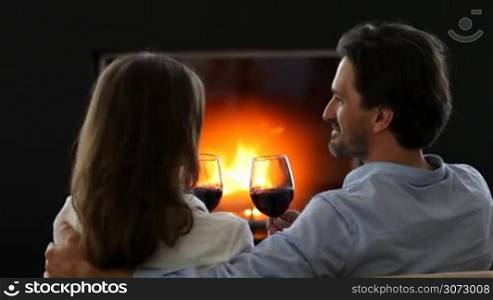Romantic couple drinking wine at home near fireplace