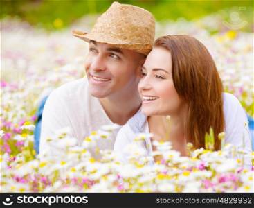 Romantic couple having fun at spring park, cheerful family enjoys countryside vacation, happy boyfriend and girlfriend laying down in garden of flower field, smiling faces, love concept