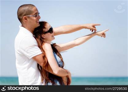 Romantic Couple holding each other and pointing at the sea