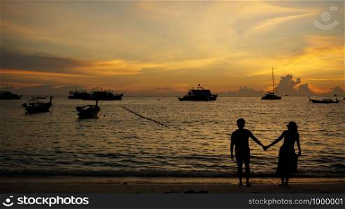 Romantic couple honeymoon travel banner on beach at sunset during travel. Happy woman and man holding hands playful in romance in beautiful sun light