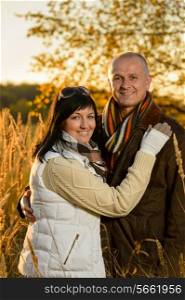 Romantic couple hugging in autumn countryside backlit by sunset