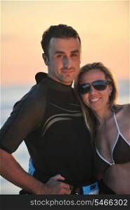 romantic couple in surf wear posing at beach on sunset at summer season