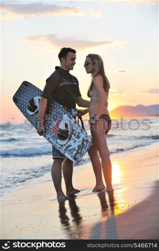 romantic couple in surf wear posing at beach on sunset at summer season