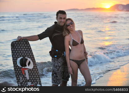 romantic couple in surf wear posing at beach on sunset at summer season