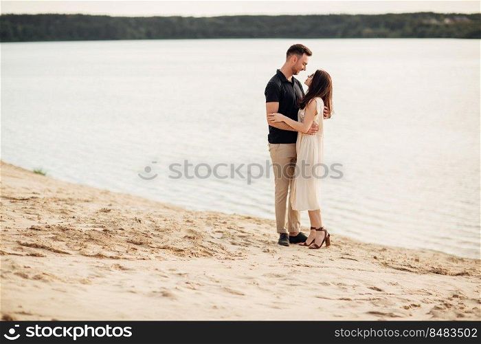 Romantic couple is hugging outdoors. elegant and stylish woman and man in love are walking along the lake. Happy moments together. love story.. Romantic couple is hugging outdoors. elegant and stylish woman and man in love are walking along the lake. Happy moments together. love story