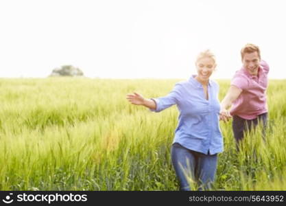 Romantic Couple Running In Field Holding Hands