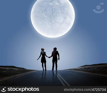 Romantic couple. Silhouettes of young romantic couple standing under the moon light