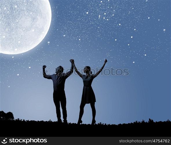 Romantic couple. Silhouettes of young romantic couple standing under the moon light