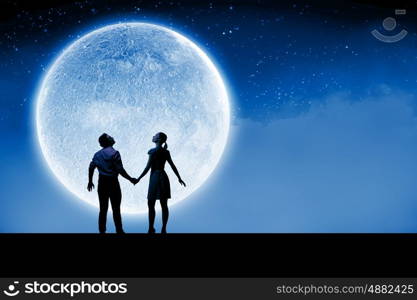 Romantic couple. Silhouettes of young romantic couple standing under the moon light