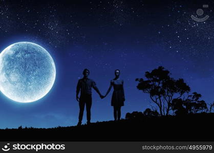 Romantic couple. Silhouettes of young romantic couple standing under the moon light