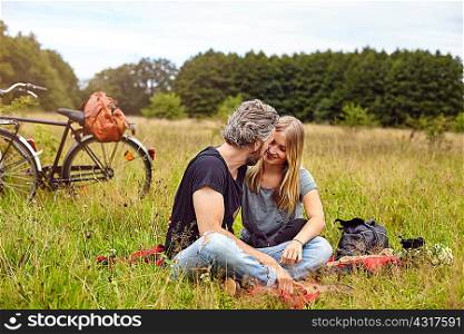 Romantic couple sitting on picnic blanket in rural field
