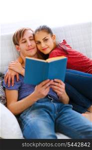 Romantic couple sitting on sofa and reading book&#xA;