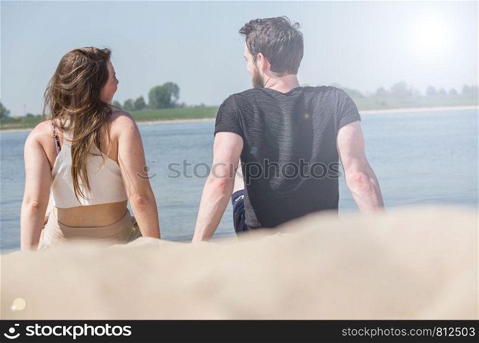 Romantic couple sitting on the beach and enjoying beautiful sea view.love and valentines concept.summer vacation concept. cute couple. Romantic couple sitting on the beach and enjoying beautiful sea view.love and valentines concept.summer vacation concept.