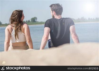 Romantic couple sitting on the beach and enjoying beautiful sea view.love and valentines concept.summer vacation concept. cute couple. Romantic couple sitting on the beach and enjoying beautiful sea view.love and valentines concept.summer vacation concept.
