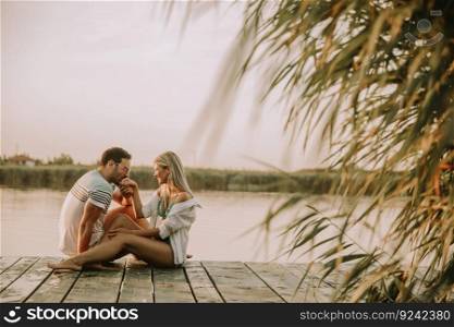 Romantic couple sitting on the wooden pier on the lake at sunny day