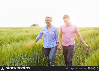Romantic Couple Walking In Field Holding Hands