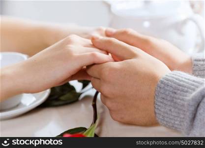 Romantic date. Close up image of young couple holding hands having date at cafe