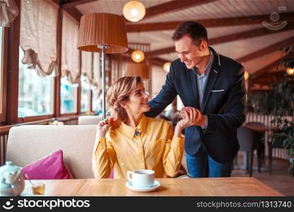Romantic date of love couple in restaurant. Man in suit hugs beautiful woman