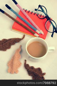 Romantic desk with ornament from handmade product, lily flower knit from white yarn, handbook, knitting pencil, coffee cup, glasses, beautifil craft