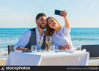 Romantic dinner on the beach, couple on honey moon make a selfie. Celebration concept.. couple on the beach the Valentine&rsquo;s day
