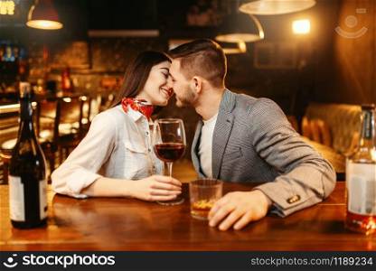 Romantic evening in bar, love couple kissing at wooden counter. Lovers leisures in pub, husband and wife relaxing together in nightclub