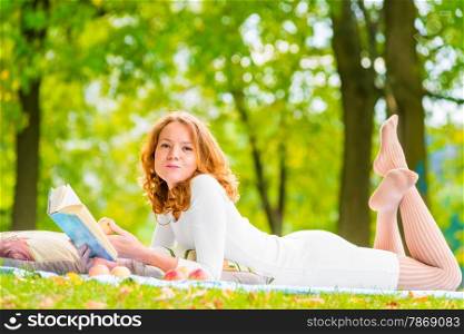 romantic girl with a good book and a delicious apple in the park