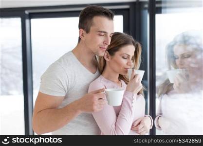 romantic happy young couple enjoying morning coffee by the window on cold winter day at home