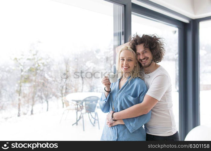 romantic happy young couple enjoying morning coffee by the window on cold winter day at home