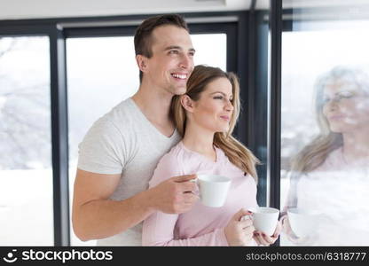 romantic happy young couple enjoying morning coffee by the window on cold winter day at home