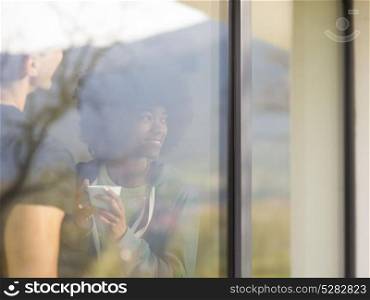 romantic happy young multiethnic couple enjoying morning coffee by the window in their luxury home