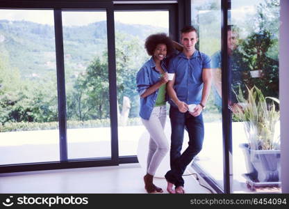 romantic happy young multiethnic couple enjoying morning coffee by the window in their luxury home