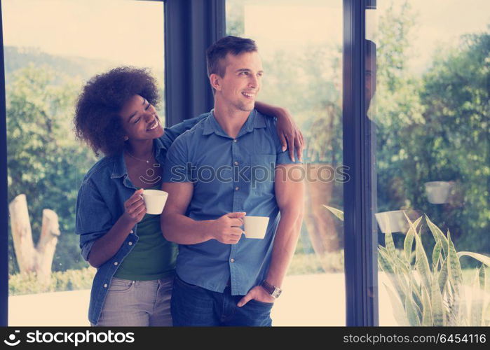 romantic happy young multiethnic couple enjoying morning coffee by the window in their luxury home