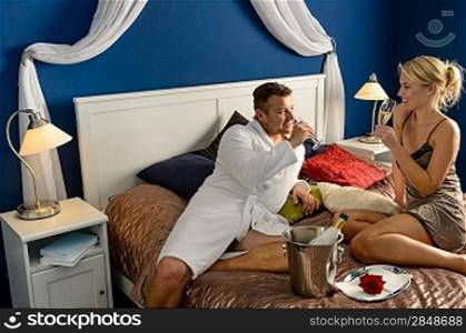 Romantic hotel room young couple sexy nightgown robe drinking champagne