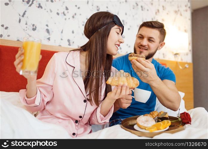 Romantic love couple, breakfast in bed at home, good morning, caring husband. Harmonious relationship in young family. Man and woman resting together in their house, carefree weekend. Romantic couple, breakfast in bed, caring husband