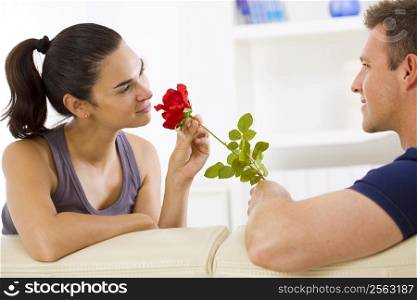 Romantic man giving red rose to woman at home, smiling.