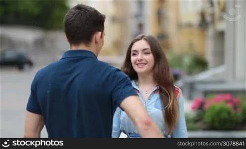 Romantic man hiding amazing bouquet of flowers for girlfriend behind his back. Excited surprised woman receiving bunch of flowers from beloved hipster teenager while meeting outdoors on romantic date. Smiling girl kissing her boyfriend.