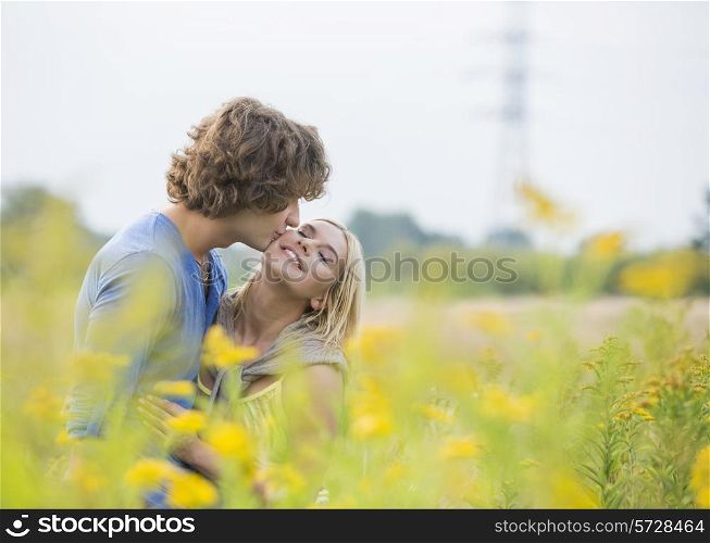 Romantic man kissing woman in field