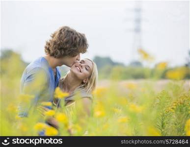 Romantic man kissing woman in field
