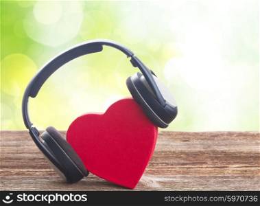 Romantic music concept - red heart with headphones with green background. Romantic music concept